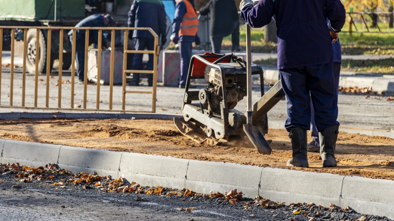 worker compresses sand for paving slabs with special working tool - tamping machine or vibratory plate. Repair of pavement pavement. Preparation of the surface for laying paving slabs