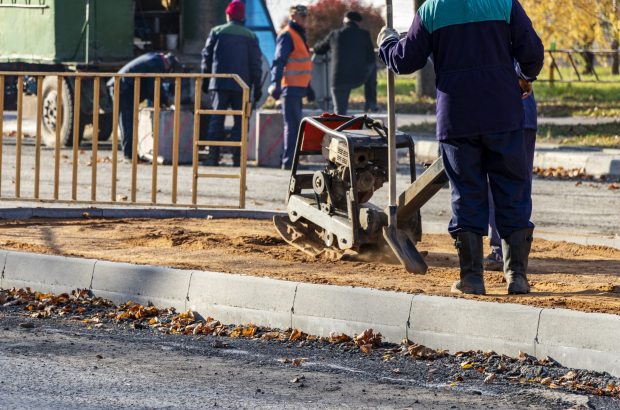 worker compresses sand for paving slabs with special working tool - tamping machine or vibratory plate. Repair of pavement pavement. Preparation of the surface for laying paving slabs