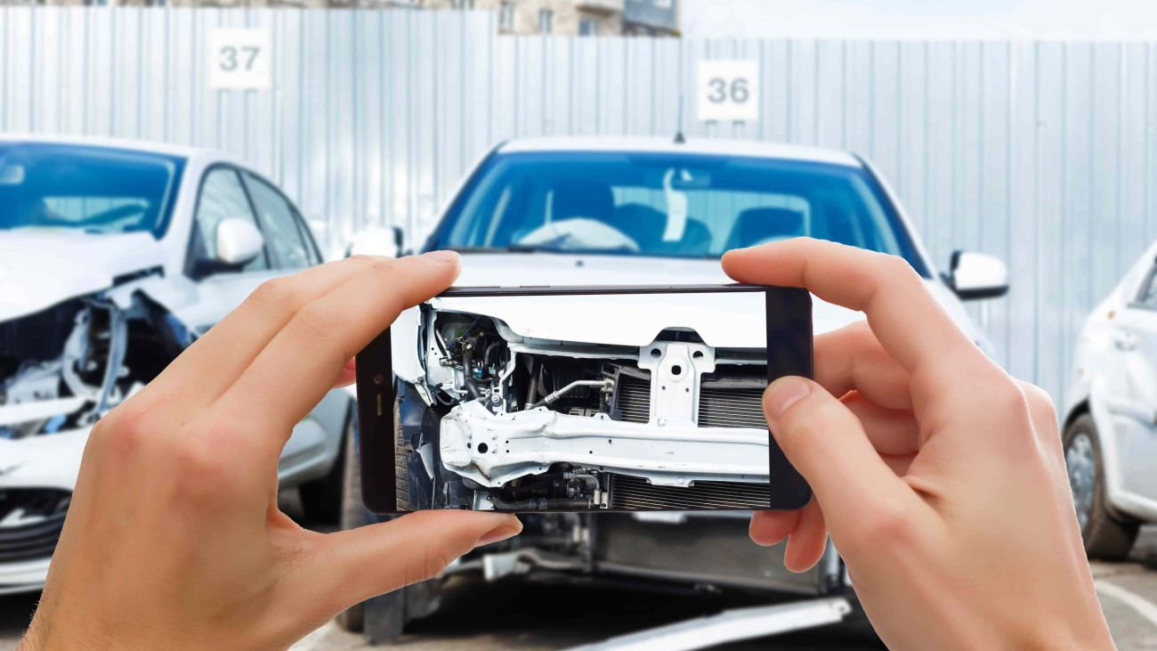 man_photographing_his_vehicle_with_damages_accident_insurance_with