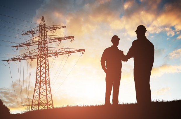 Silhouette,Of,Two,Engineers,Shaking,Hands,With,Electricity,Pylon,Against