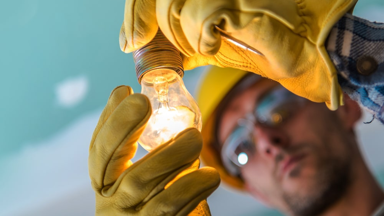 close-up-man-repairing-illuminated-light-bulb 1-min