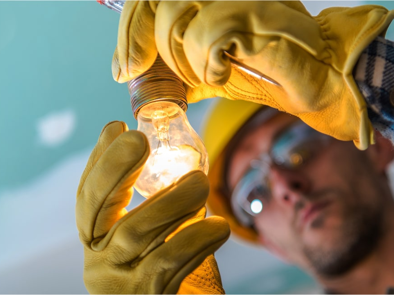 close-up-man-repairing-illuminated-light-bulb 1-min