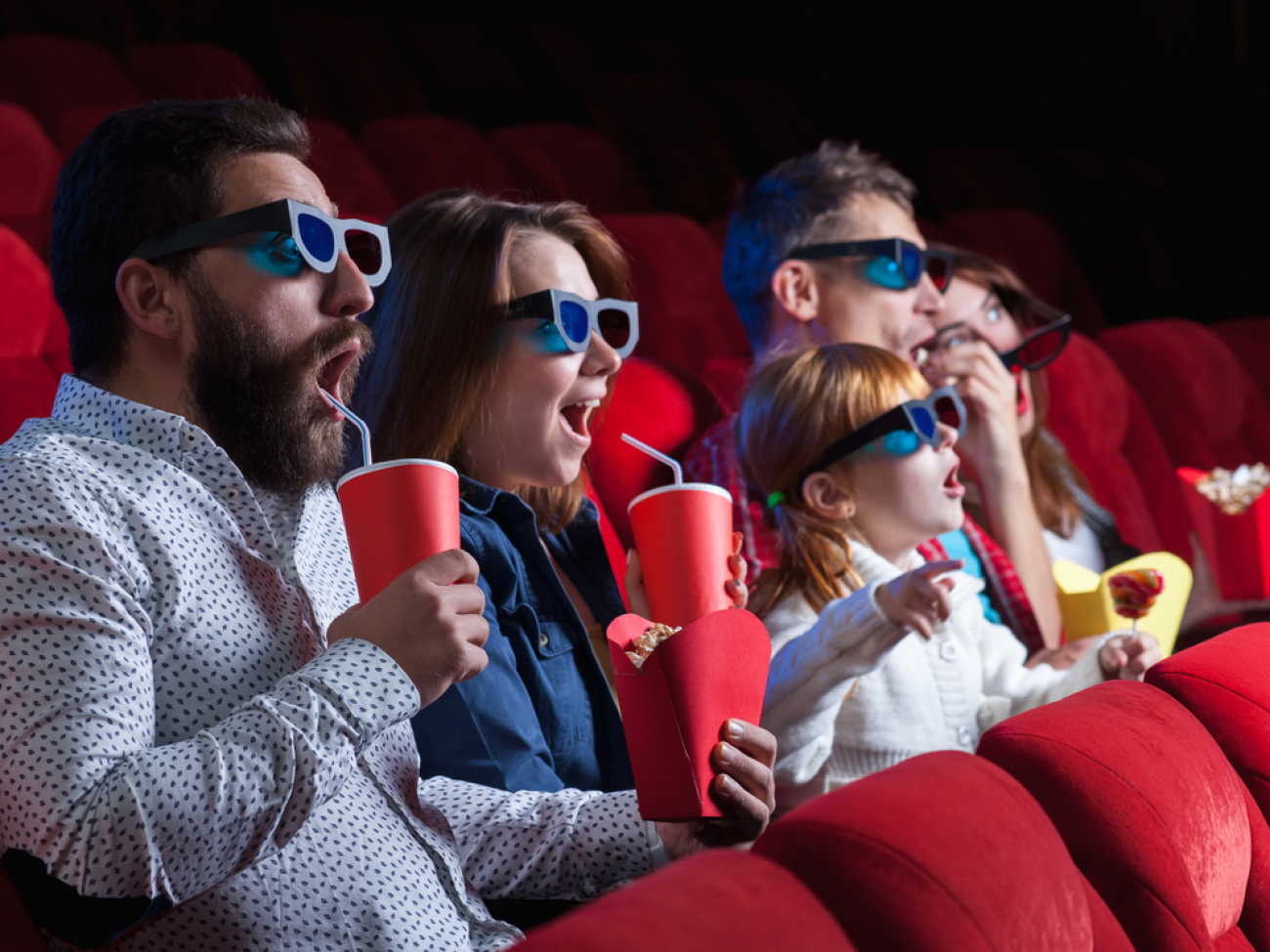 A variety of human emotions of friends holding a cola and popcorn in the cinema.