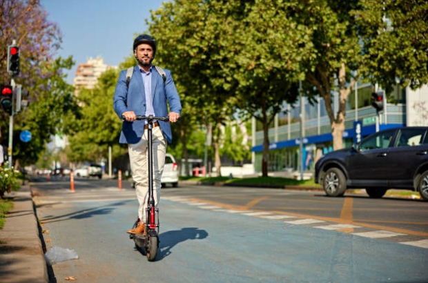 Full length front view of environmentally aware office worker wearing backpack, safety helmet, and riding in downtown district.